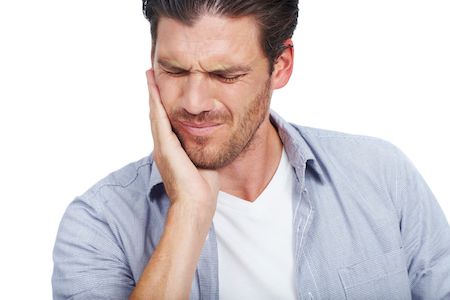 man holding his mouth because of tooth pain